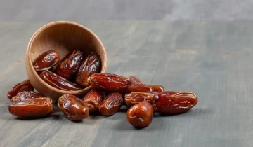 Sweet dates out of wooden bowl on marble background